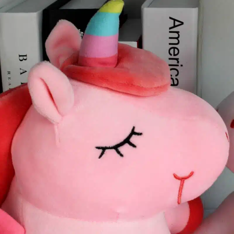PELUCHE LICORNE LUMINEUSE ROSE AILÉE 19 PELUCHE LICORNE LUMINEUSE ROSE AILÉE GROS PLAN SUR LA TÊTE