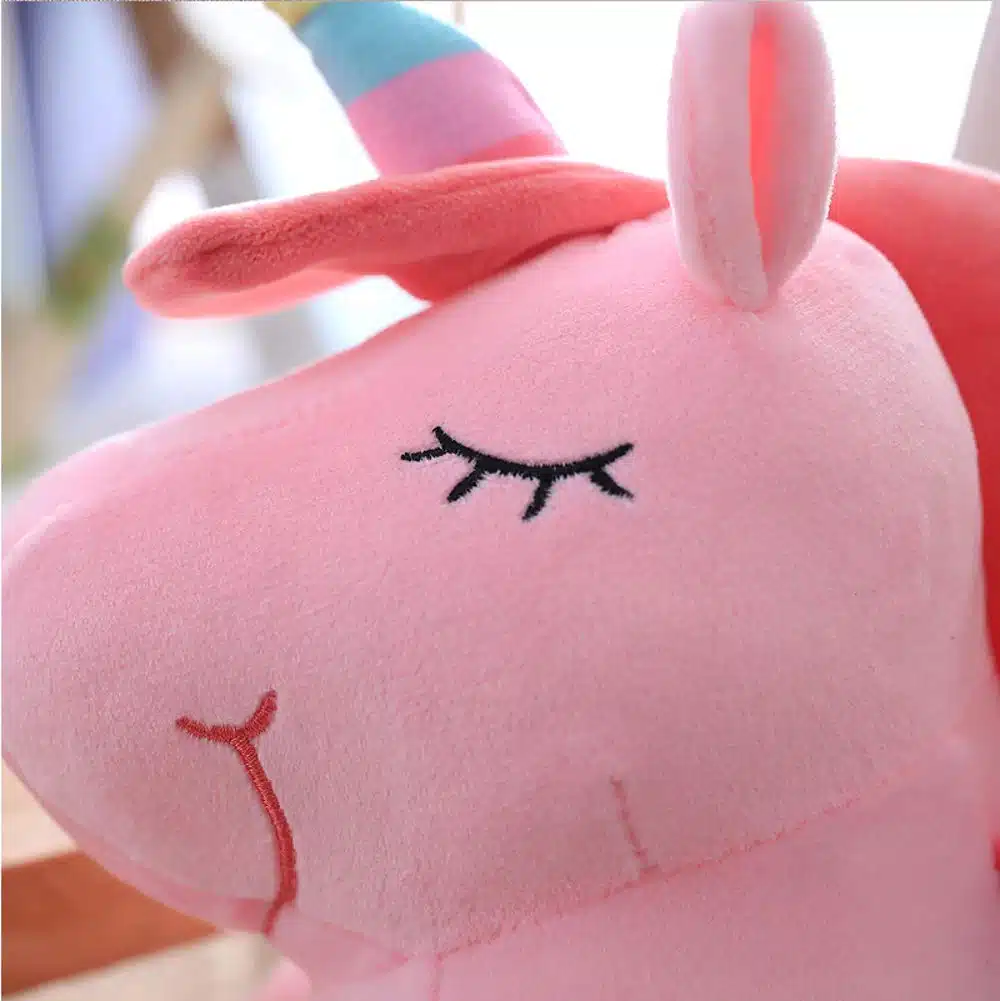 PELUCHE LICORNE LUMINEUSE ROSE AILÉE 3 PELUCHE LICORNE LUMINEUSE ROSE AILÉE VU DE LA TÊTE DE PRÊT
